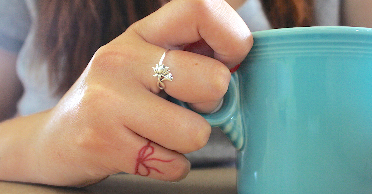 Tiny bow tattoo on ring finger